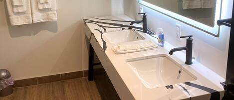 Un baño con un lavabo blanco, un espejo grande y un perchero para toallas.