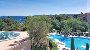 A swimming pool with lounge chairs, a glass-enclosed area, and a view of the sea. - Les Calanques Spa Thalassothérapie by Interhome (Les Issambres)