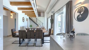 Un interior moderno con comedor, escalera y un aplique de pared.
