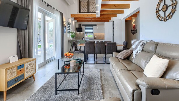 Una sala moderna con sofá, televisor y un comedor con sillas y mesa.
