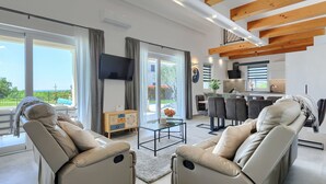 Una sala de estar moderna con sillones de cuero, un televisor de pantalla plana y una zona de cocina.