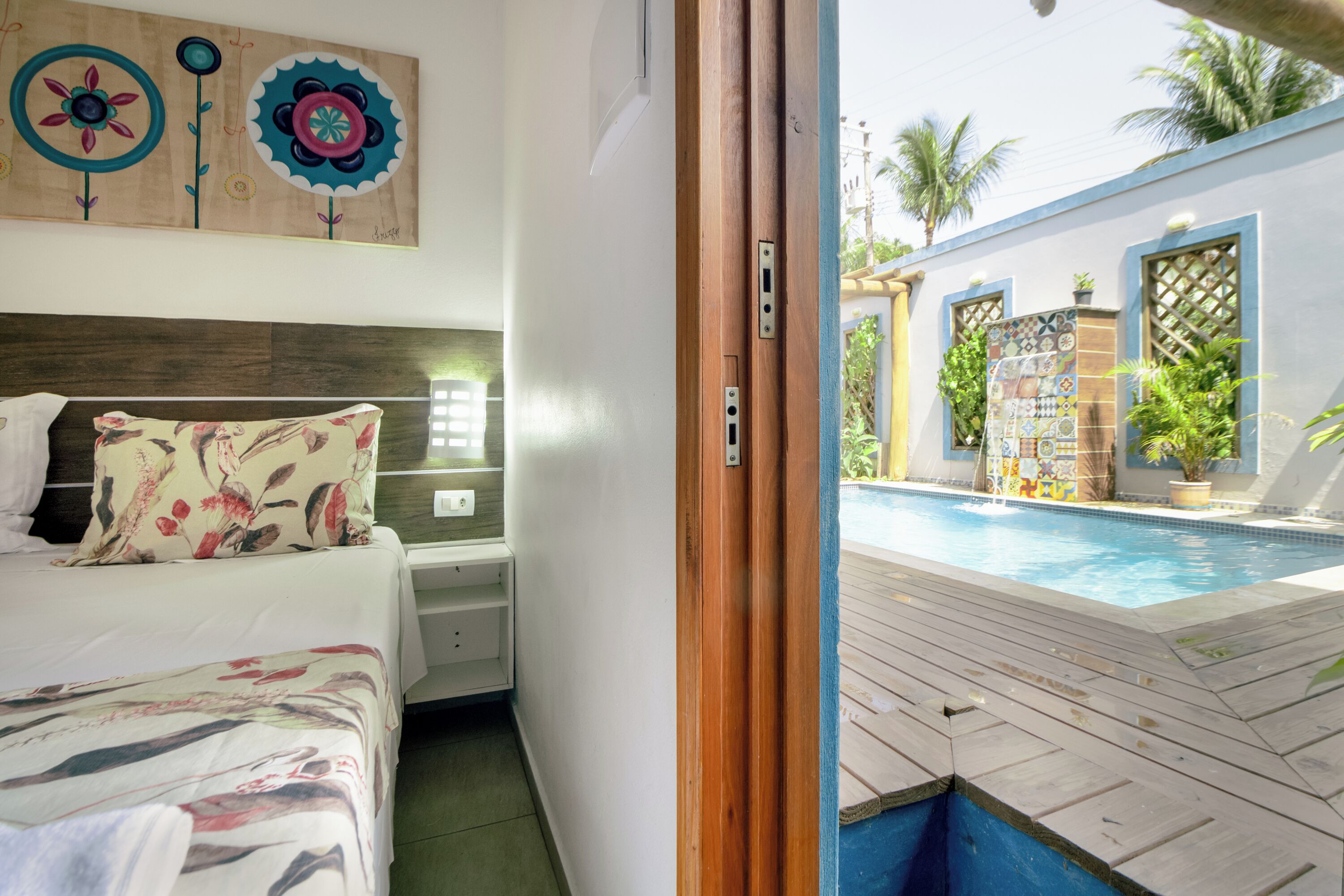 Une chambre d’hôtel avec un lit, une table de chevet et une vue sur l’espace extérieur abritant une piscine.