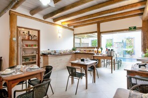 A restaurant with wooden beams, tiled floors, and a buffet area with various food items. - Velinn Pousada Iguana Azul (Ilhabela)