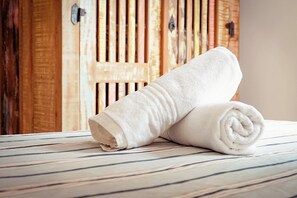 A neatly rolled white towel on a striped bed.