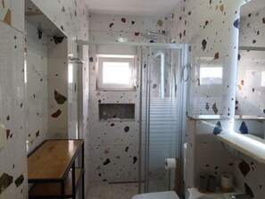 A bathroom with terrazzo flooring, a shower enclosure, a toilet, and a sink with a mirror. - Apartment Zorić by Interhome (Privlaka)