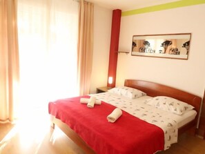 A hotel room with a bed, curtains, a nightstand, a lamp, and a framed picture on the wall. - Apartment Zorić by Interhome (Privlaka)