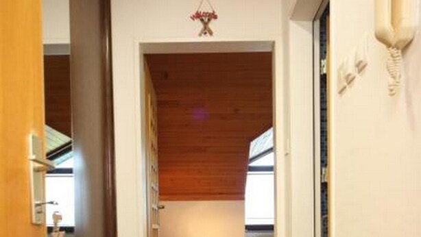 A narrow hallway with wooden flooring leading to a bedroom with a bed and a window. - Apartment Viki (Kranjska Gora)