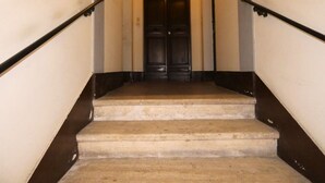 Un escalier avec une rampe sombre et une porte en haut.