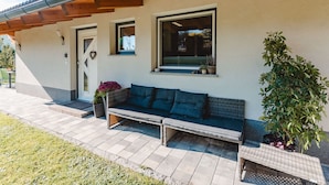 A modern house with a patio area featuring a sofa and potted plants. - Fankhauser by Interhome (Kaprun)