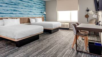 Een hotelkamer met twee bedden, een bureau en een stoel.