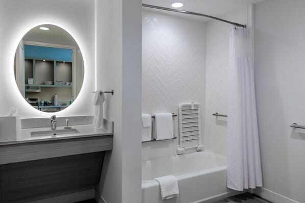 A modern bathroom with a vanity, a bathtub, and a shower curtain.
