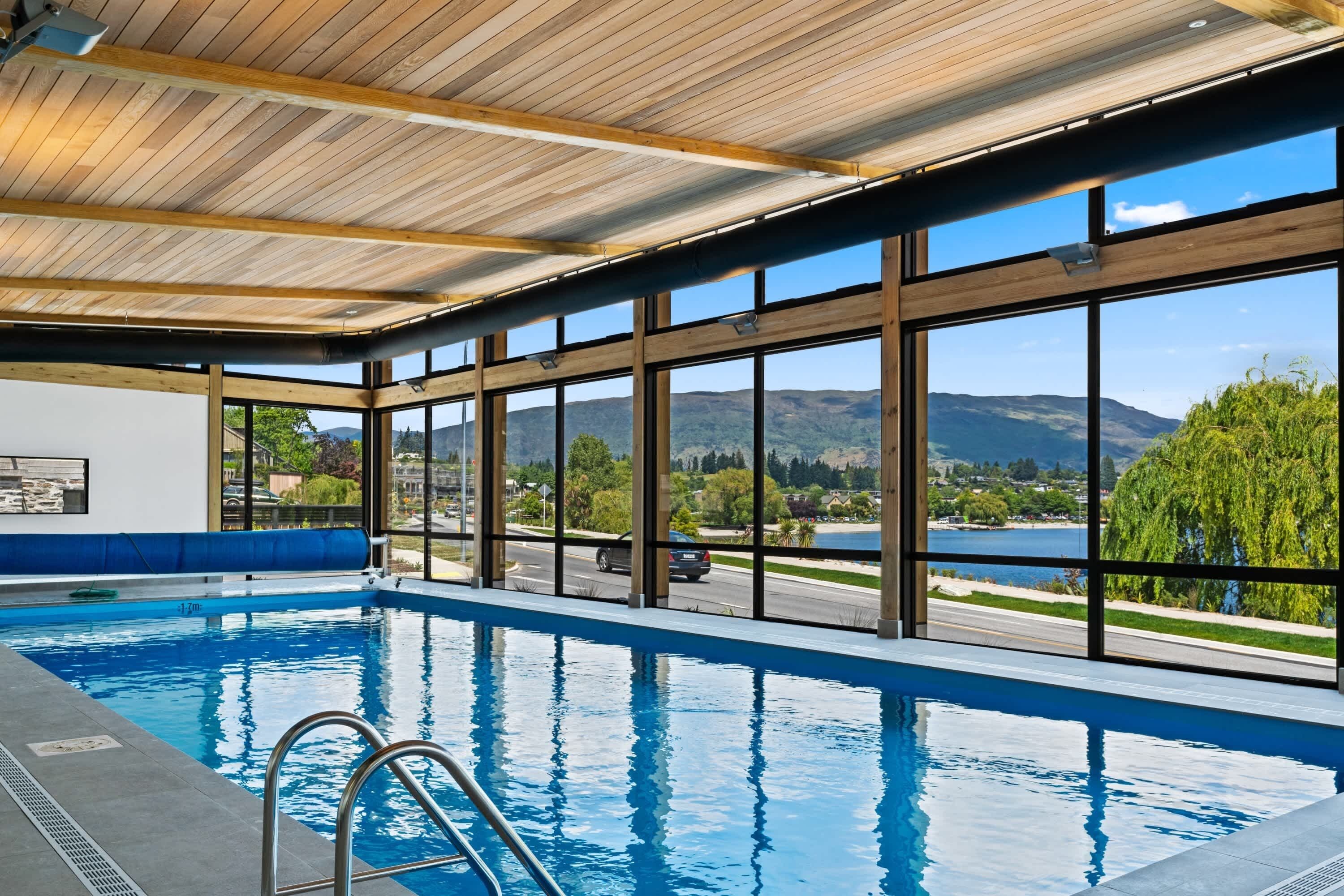 An indoor swimming pool with a view of a lake and mountains.