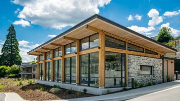A modern building with large windows, a stone facade, and a wooden roof.