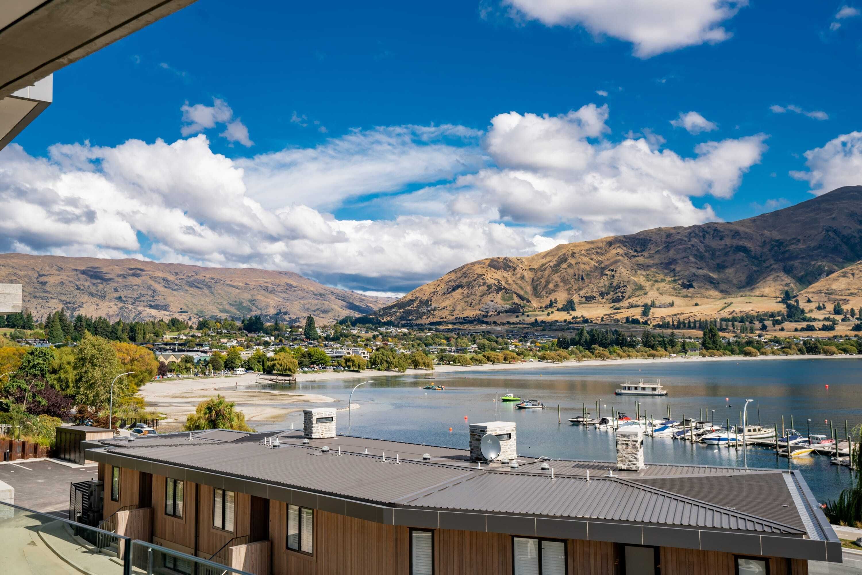 A modern building with a view of a lake, mountains, and a marina.