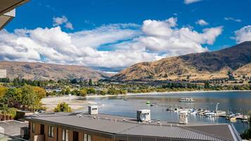 A modern building with a view of a lake, mountains, and a marina.