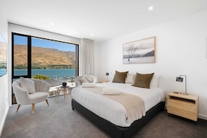Une chambre à coucher moderne avec un grand lit, une chaise, une petite table et une table de chevet.