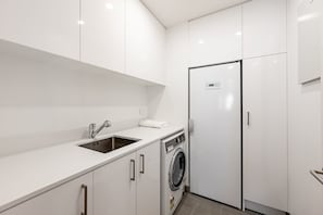 Une cuisine moderne équipée d’un évier, d’un lave-linge et d’un réfrigérateur.