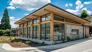 Un bâtiment moderne doté de grandes fenêtres, d’une façade en pierre et d’un toit en bois.