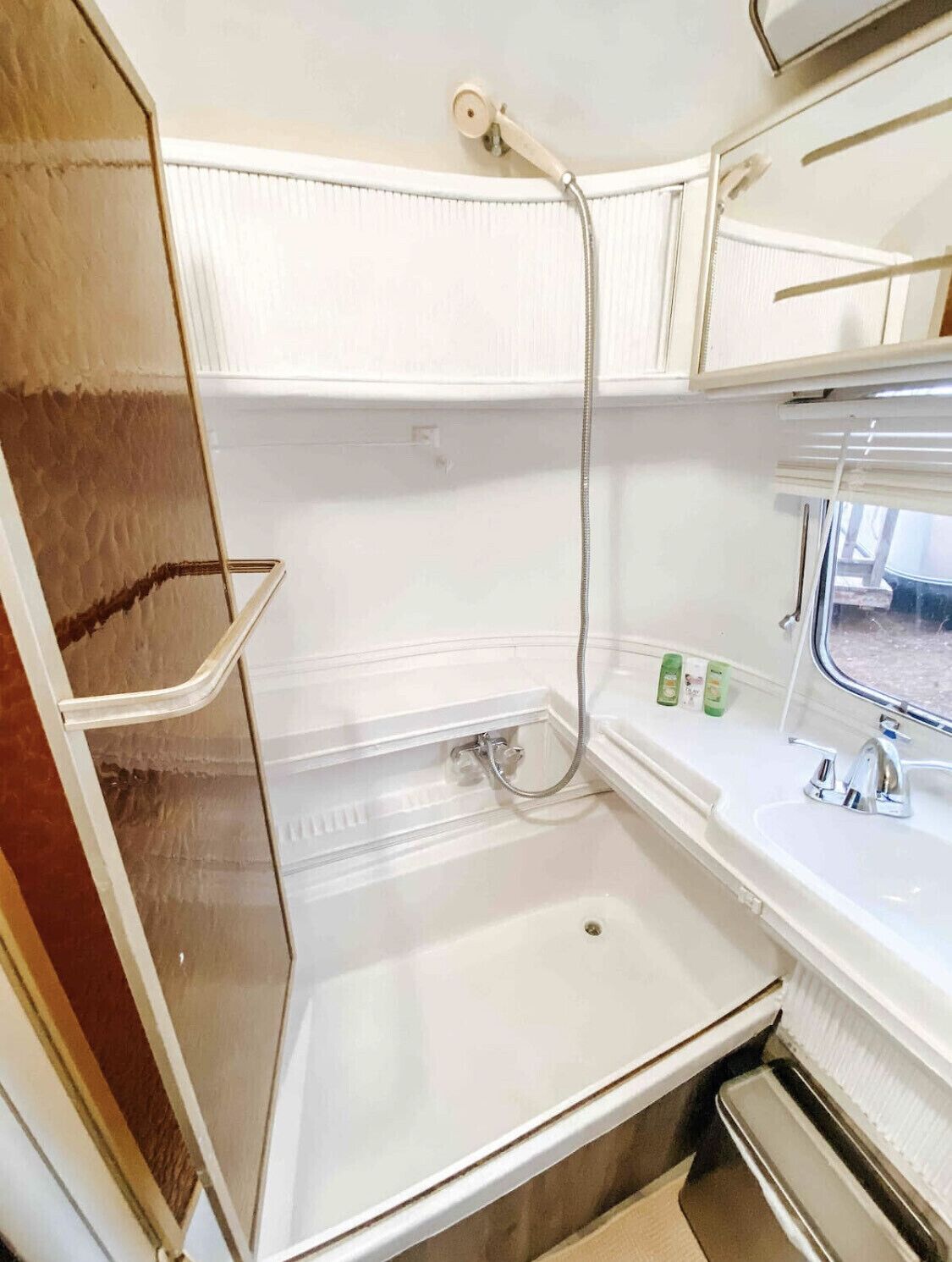 A compact bathroom with a shower, sink, and storage cabinets.