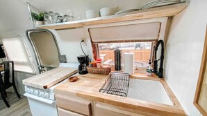 Una kitchenette compacta con estufa, lavamanos y encimera de madera.
