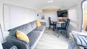 Interior compacto de una autocaravana con sofá, mesa de comedor y sillas.