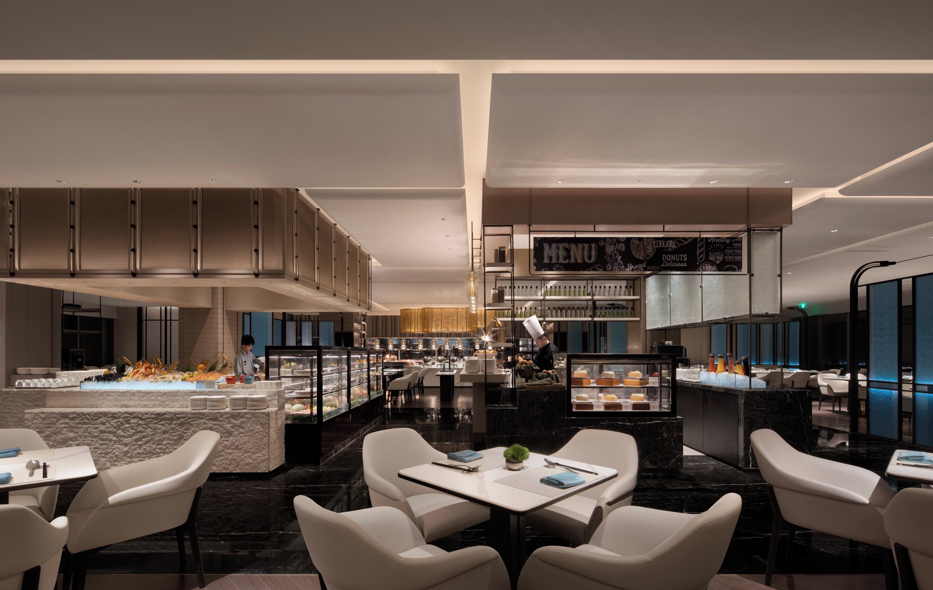 A modern restaurant with a central island, seating area, and a menu display.