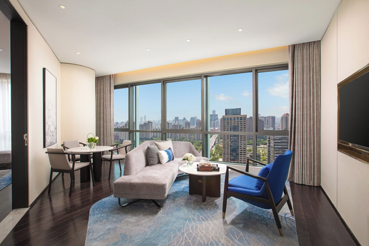 Una habitación de hotel moderna con vista a la ciudad, un comedor y un espacio de descanso.