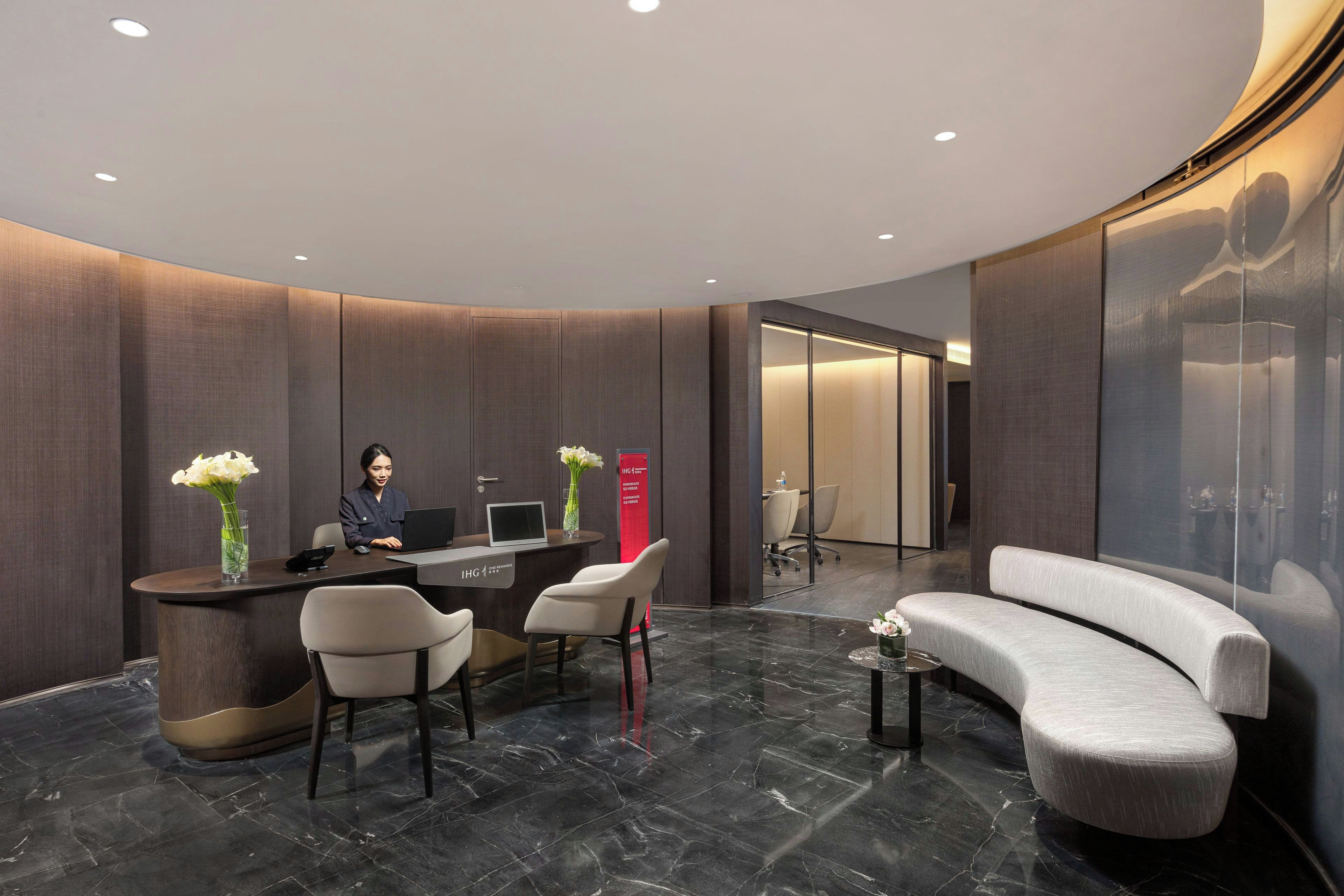 A modern reception area with a curved reception desk, seating, and a large mirror wall.