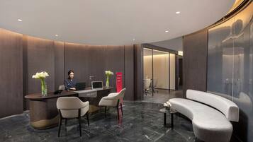 A modern reception area with a curved reception desk, seating, and a large mirror wall.