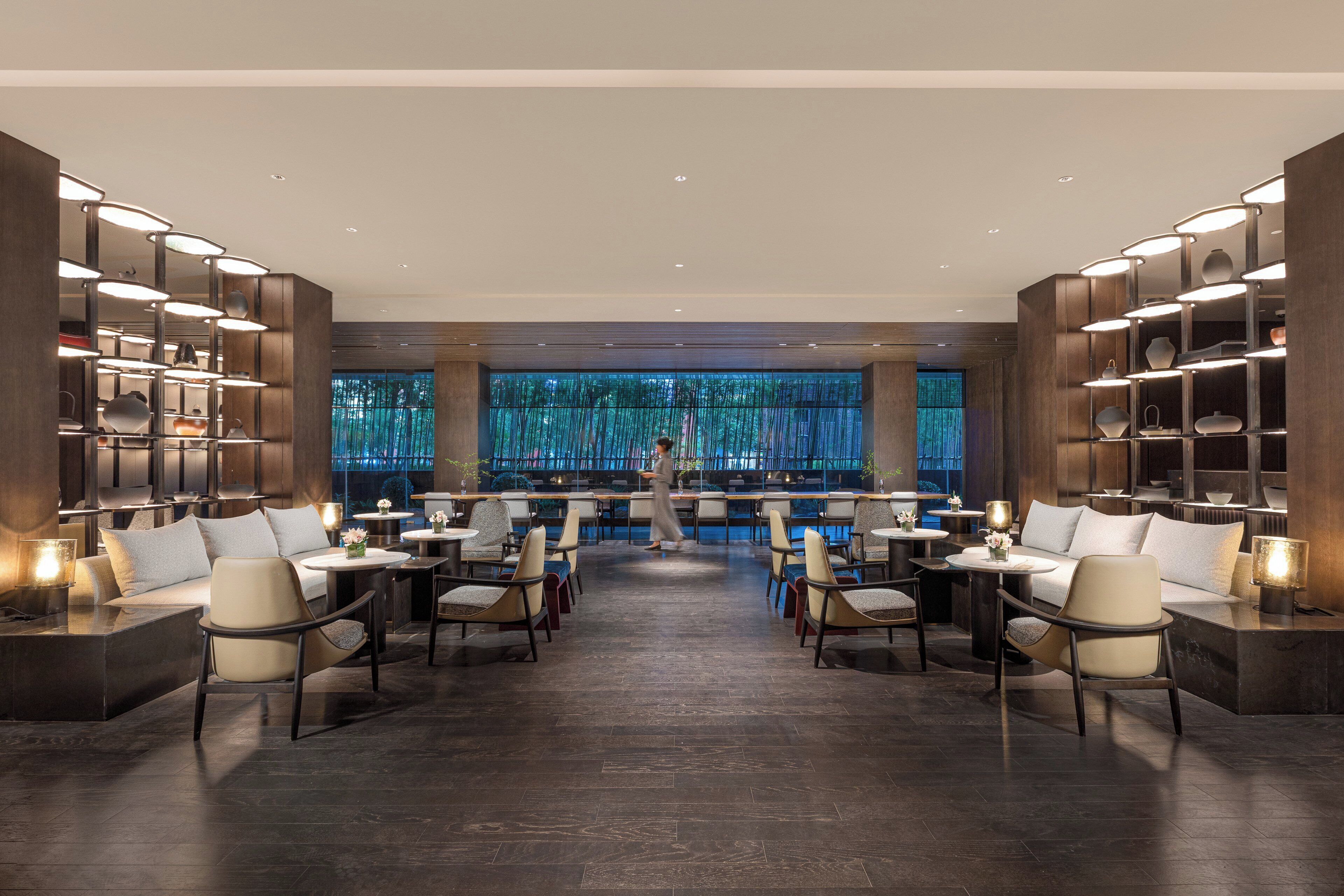 Un restaurante moderno con un pasillo central, asientos a ambos lados y estantes con adornos decorativos.
