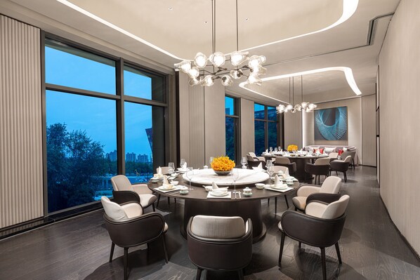 A modern dining area with a round table, multiple chairs, and a chandelier. - HUALUXE Shanghai Changfeng Park by IHG (Shanghai)
