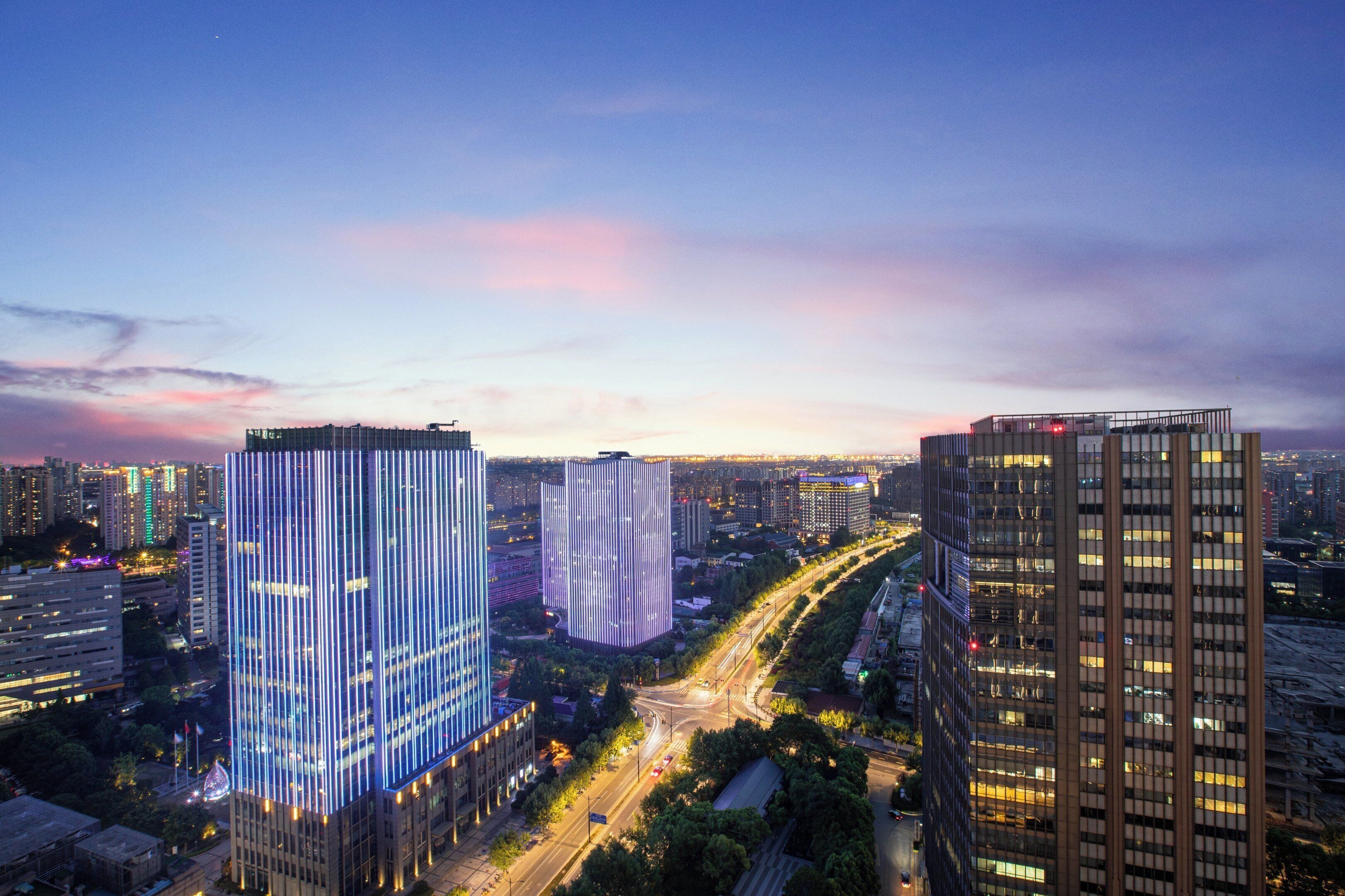 A cityscape with modern high-rise buildings, a busy road, and a clear sky.