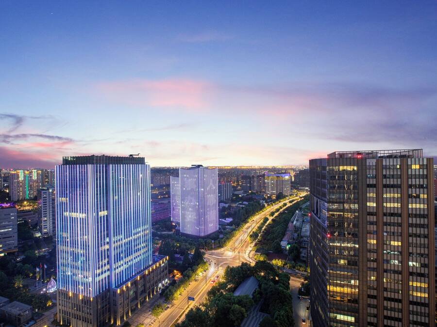 A cityscape with modern high-rise buildings, a busy road, and a clear sky.