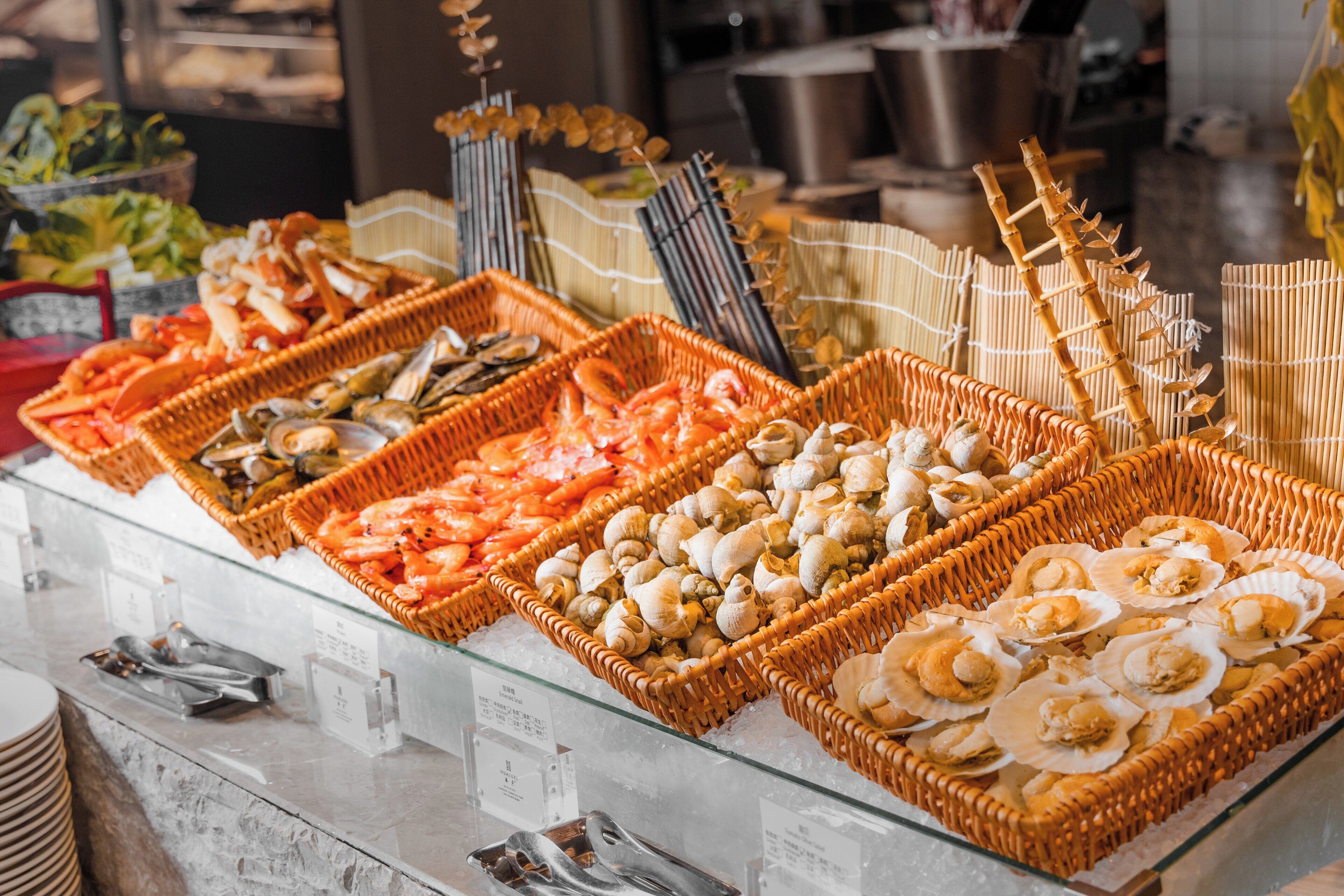 A seafood buffet with various types of shellfish and seafood displayed in wicker baskets.