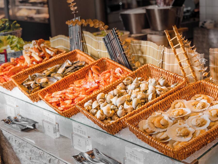 A seafood buffet with various types of shellfish and seafood displayed in wicker baskets.