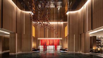 A modern lobby with a central reception desk, high ceilings, and a decorative hanging installation.