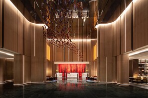 Un vestíbulo moderno con mostrador de recepción central, techos altos e instalación decorativa colgante.