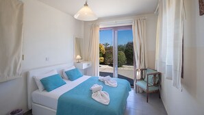 Un dormitorio con cama, una silla, un ventanal y vistas al exterior.