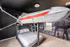 A bunk bed with a space-themed mural, a ladder, and a window.