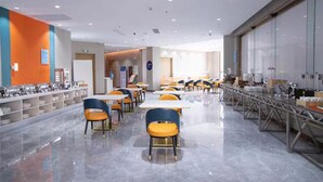 Eine moderne Cafeteria mit Tischen, Stühlen und einer Theke mit Speisen. Der Boden ist sauber und glänzend.