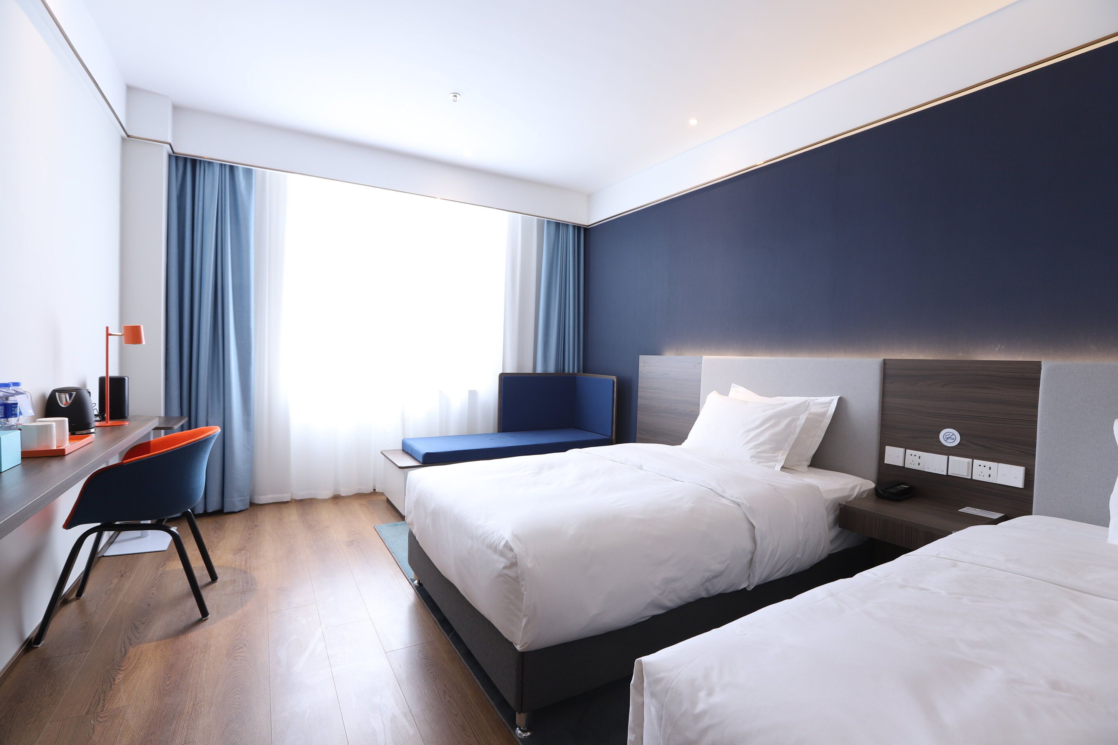 Habitación de hotel moderna con una cama grande, un escritorio con silla y vistas al exterior.
