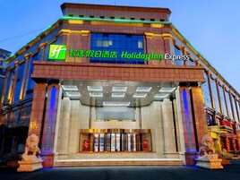 Un edificio de Holiday Inn Express con una entrada destacada, ventanas amplias y una estatua de león en la base.