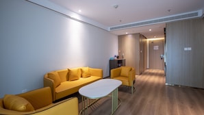 Ein modernes Hotelzimmer mit einem gelben Sofa, einem kleinen Tisch und einem Holzboden.