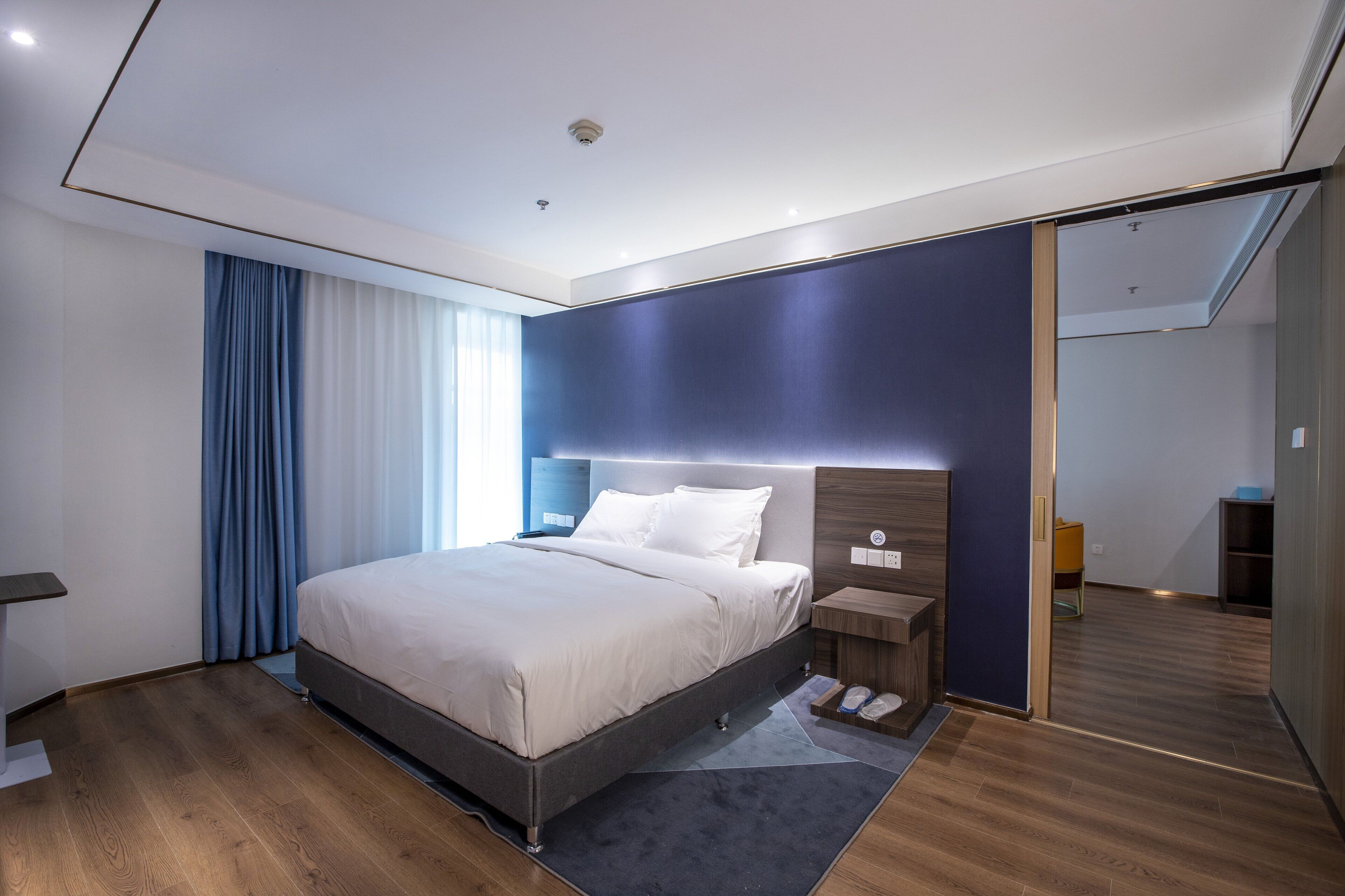 Ein modernes Hotelzimmer mit einem großen Bett, Nachttischen, einem Kleiderschrank und einem Spiegel.