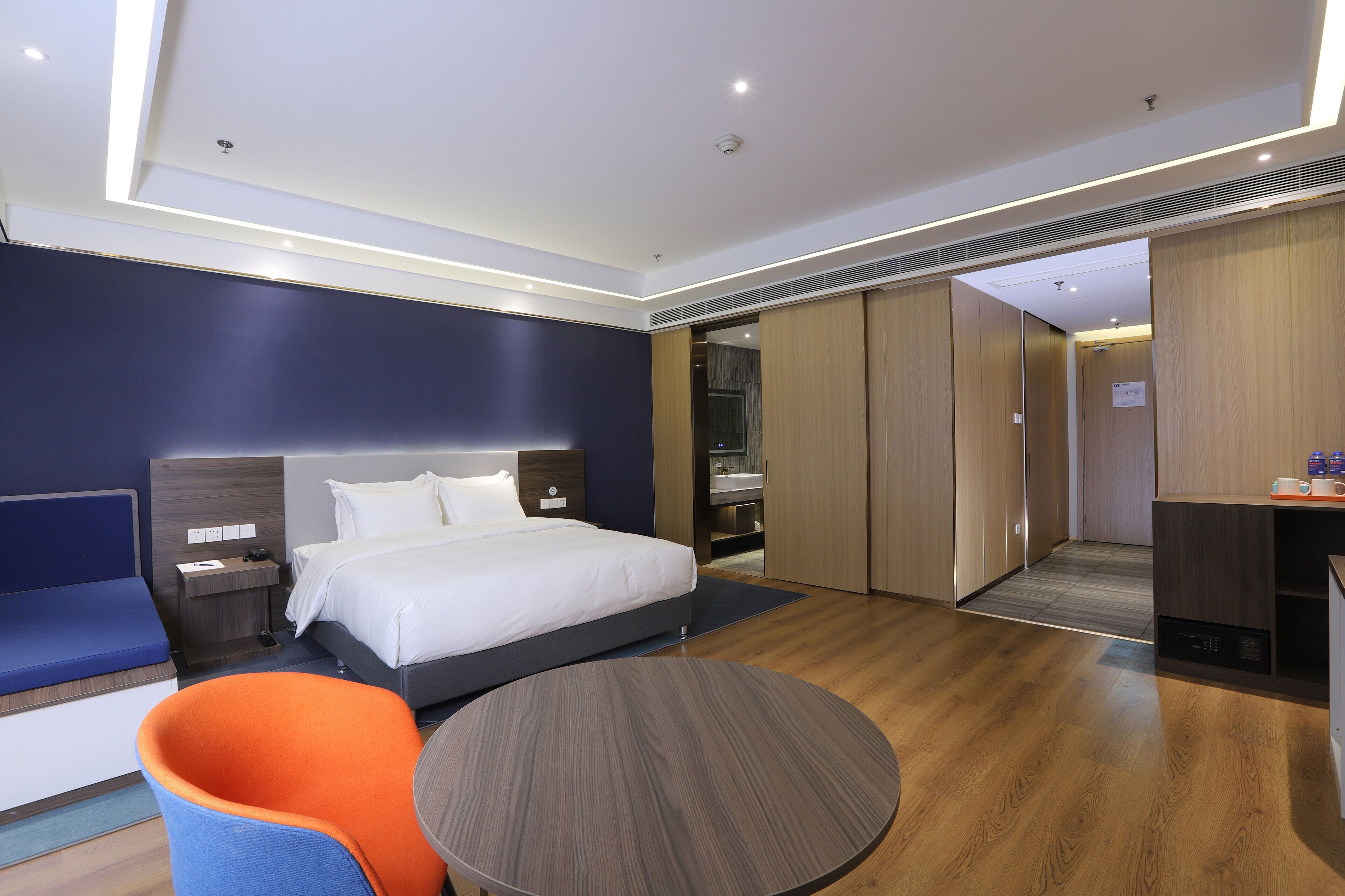 Una habitación de hotel moderna con cama, escritorio, silla y mesa redonda.