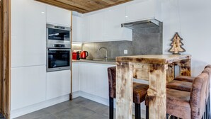 Een moderne keuken met witte kastjes, roestvrijstalen apparatuur en een houten plafond.