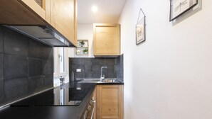 Una cocina moderna con encimeras negras, armarios de madera y un lavamanos de acero inoxidable.