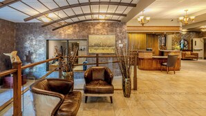 A spacious lobby with leather seating, a reception desk, and a large painting on the wall.