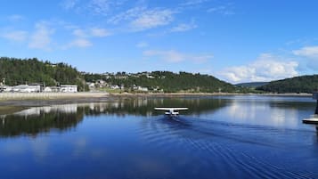 A calm lake with a small boat, a dock, and a forested hillside in the background.