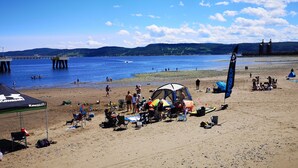 A beach with a tent, people, and a pier in the background.